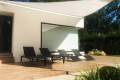 Velart Sail Shade providing shade to 4 outdoor lounge chairs beside a building