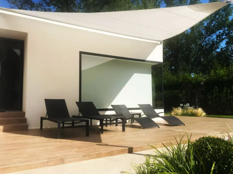 Velart Sail Shade providing shade to 4 outdoor lounge chairs beside a building