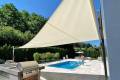 Velart Sail Shade next to a pool providing shade to the grilling area