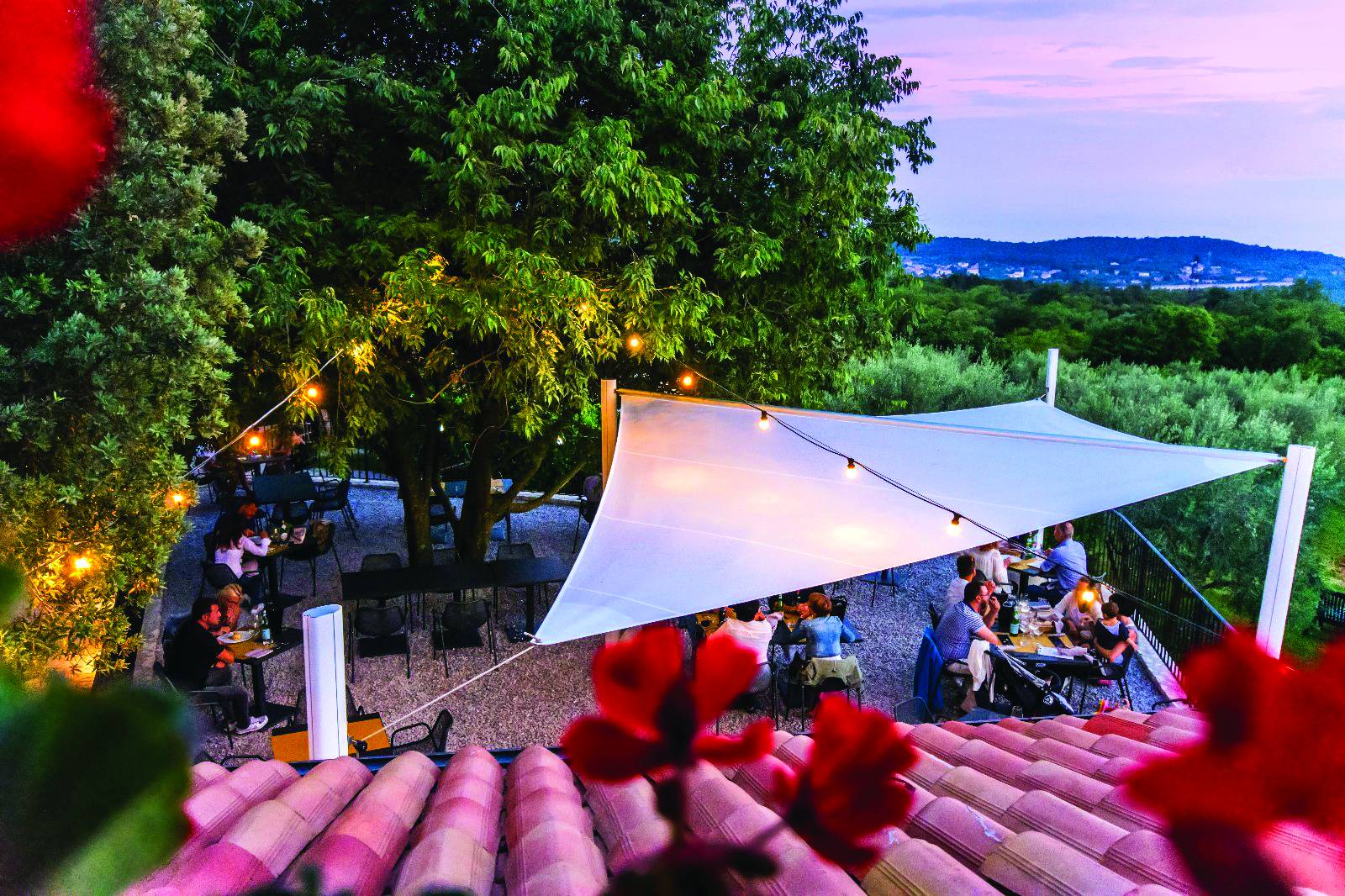 People dining outdoors underneath a Velora Sail Shade