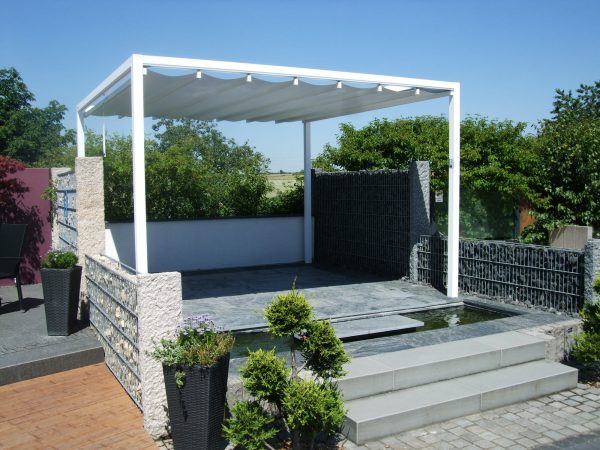 an elevated Retractable Roof Poolside Cabana behind a small pond and surrounded by retaining walls