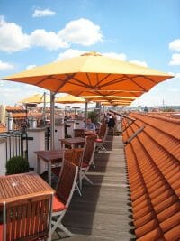p6 square duo umbrella covering small tables on a rooftop dining area