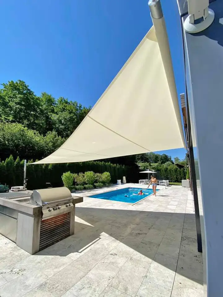Velart Sail Shade next to a pool providing shade to the grilling area