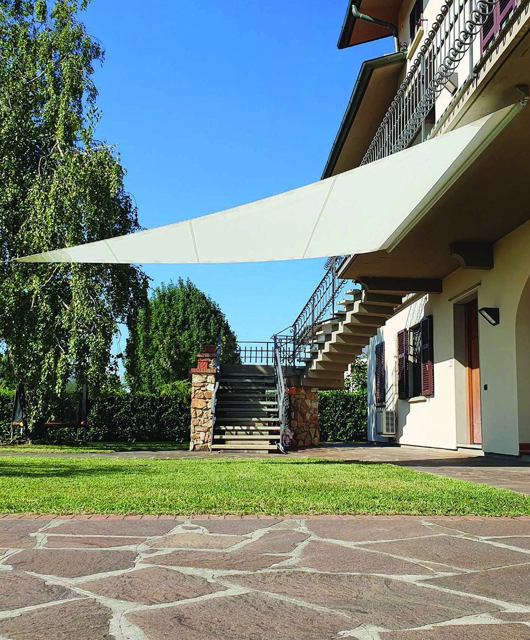 Velart Sail Shade attached to the underside of a deck and overhanging a grassy area
