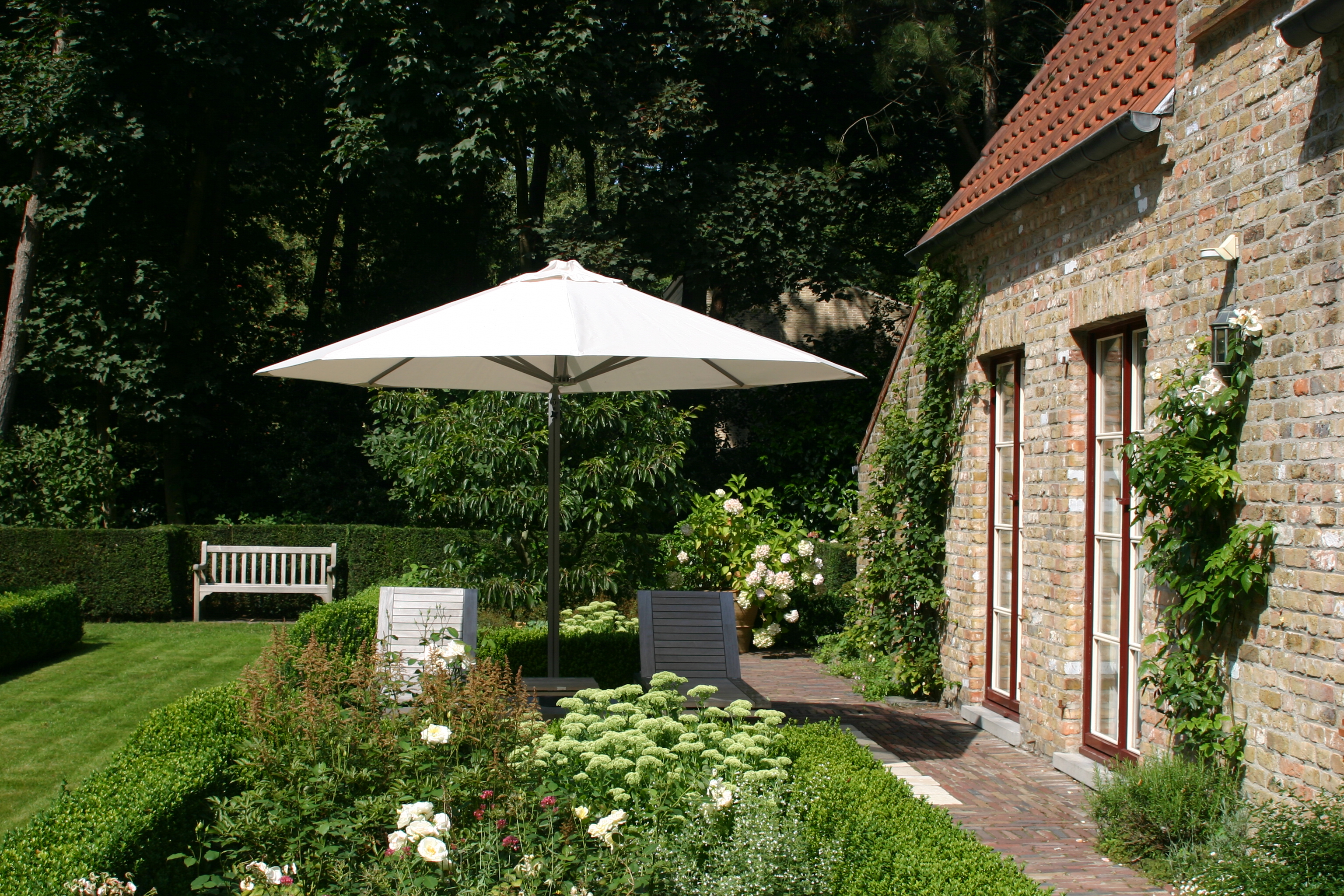 P7 umbrella with white canopy shading an outdoor seating area in a garden