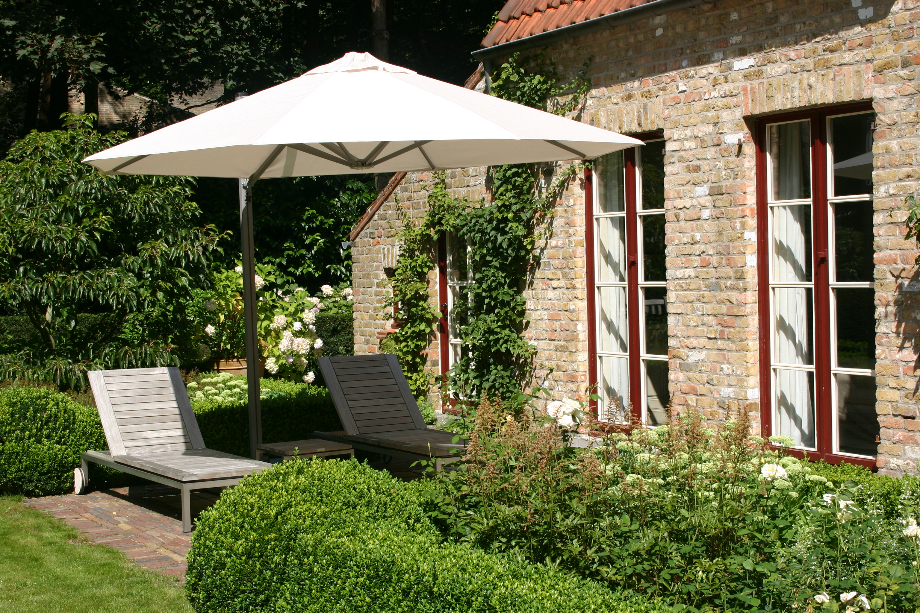 P7 umbrella with white canopy shading an outdoor seating area in a garden